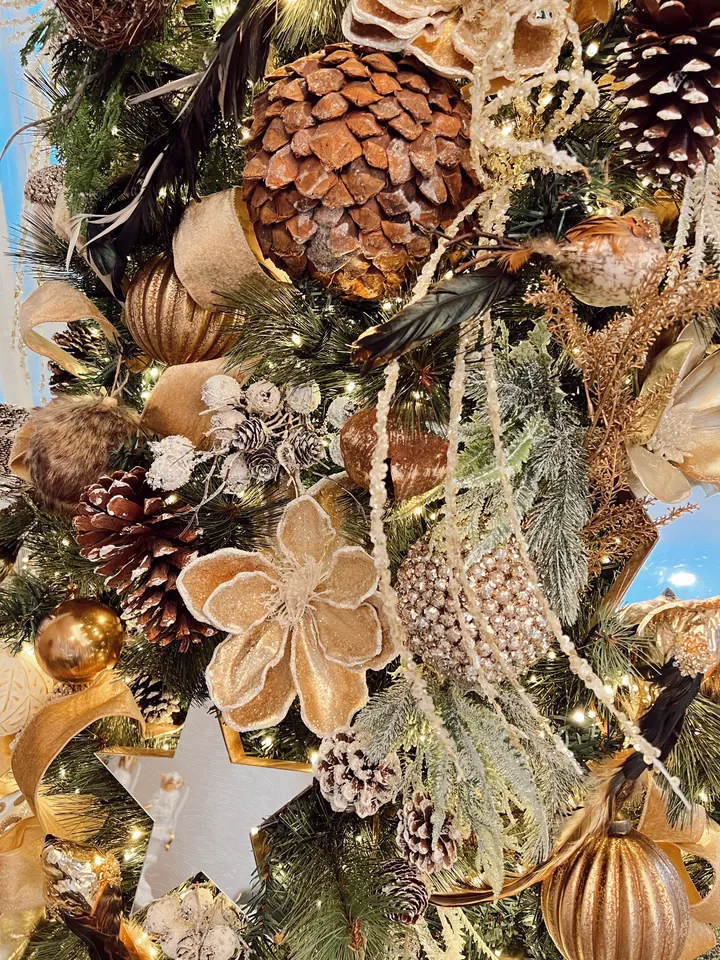 Detalle de piñas, flores doradas y luces cálidas en una decoración de Neaf